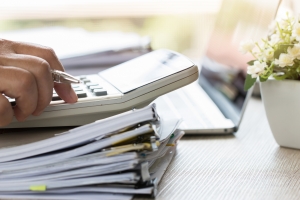 Accountant hand use calculate financial report, counting on calculator for checking financials analyzing documents paperwork with laptop computer in modern office, Accounting planning budget concept