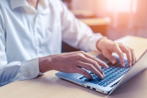 Businessman hand typing on computer keyboard of a laptop computer in office. Business and finance concept.